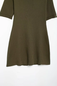 Detail of olive green short-sleeve knit dress with ribbed texture and flared hemline