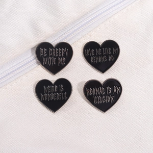Set of four black heart enamel pins with gothic lettering on white canvas background