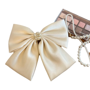 Elegant champagne satin bow hair clip with central pearl flower on a white background