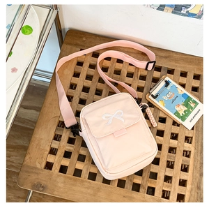 Pink canvas crossbody bag featuring adjustable strap and sweet bow embroidery detail