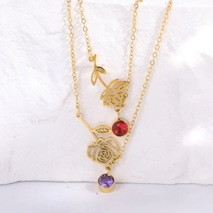 Macro detail of gold floral birthstone necklace with rose pendant and zircon charms