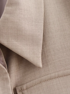 Macro detail of high-quality khaki jacket showing refined stitching and fabric texture