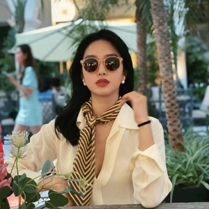 Fashion lifestyle view of a model wearing retro large pearl earrings and silk scarf