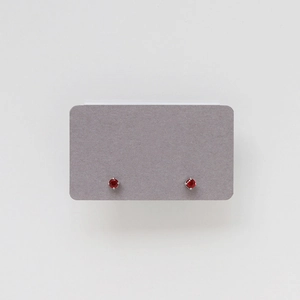 Detailed view of red gemstone stud earrings with silver four-prong setting
