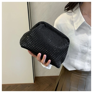 Detail of a black rhinestone evening clutch bag held against a white shirt for elegance