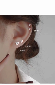 Three sizes of 999 silver heart stud earrings with cubic zirconia on model's ear