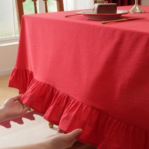 Detailed view of elegant red tablecloth featuring delicate ruffled edges and fabric texture