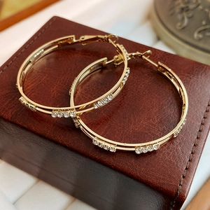 Macro view of gold-toned double-layer geometric hoop earrings with sparkling rhinestones