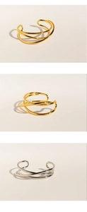Dettaglio ravvicinato di bracciali metallici incrociati multistrato in oro e argento