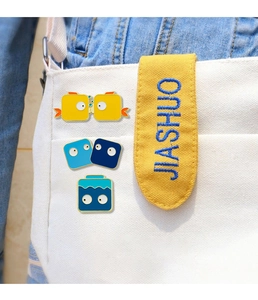 Close-up of cute cartoon fish enamel pins decorated on a canvas bag strap with person