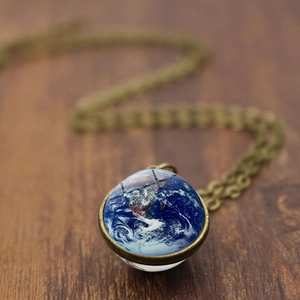 Earth glass ball pendant necklace with bronze chain on dark wood background