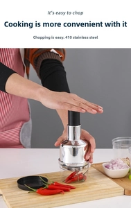 Dettaglio di mani che premono il tritatutto manuale in acciaio inox 410 su un tagliere