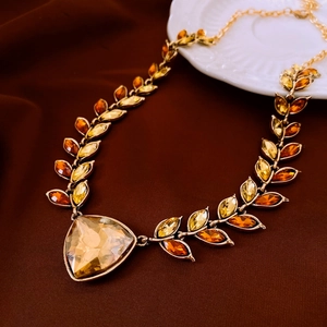 Macro shot of gold wheat ear necklace with amber gemstone on luxury brown velvet surface