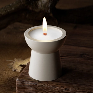 Macro detail of burning wood wick inside a white matte ceramic candle cup with soft flame