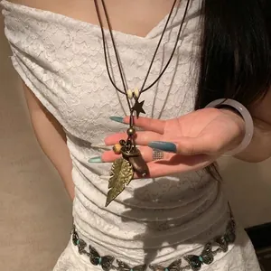 Macro detail of bronze leaf pendant with wooden beads on brown leather cord necklace
