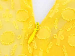 Detail eines gelben Jacquard-Netzkleides mit verdecktem Reißverschluss und Textur