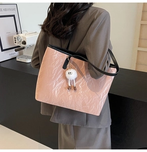 Dettaglio borsa tote rosa stropicciata con tracolla nera e ciondolo di peluche bianco