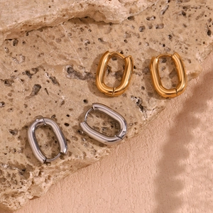 Polished 18K gold and silver U-shaped hoop earrings on a natural stone background