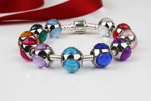 Dettaglio di perle di cristallo colorate su un bracciale a catena argento con nastro