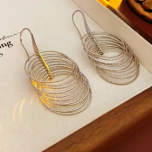 Detailed view of silver multi-layer circular hoop earrings resting in a beige jewelry box