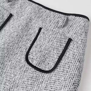 Detailed macro view of gray tweed fabric texture with black faux-leather trim and pocket