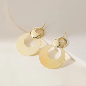Macro view of gold geometric earrings with layered hollow round discs on a white background