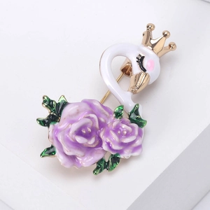 Detailed view of swan brooch with golden crown and purple enamel roses on white surface