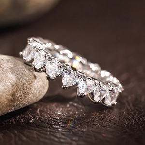 Detailed close-up of heart-shaped zircon eternity ring on natural pebble stone