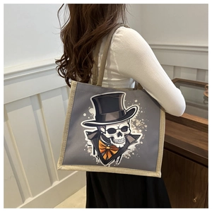 Détail porté de ce sac cabas gris en toile avec un motif de crâne stylé et chapeau