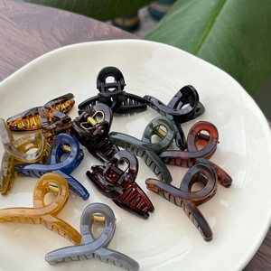 Close-up of assorted mini hair claws in various colors displayed on a ceramic plate
