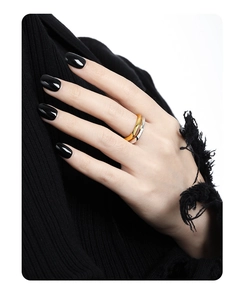 Detail of stacked two-tone silver and gold wavy rings on a hand against dark knitwear