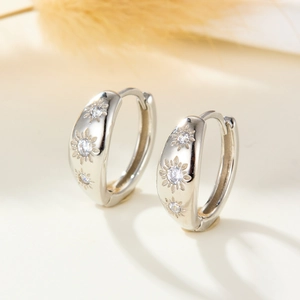 Macro detail of S925 sterling silver hoop earrings with starburst zircon engraving