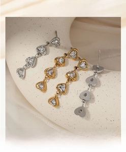Detailed view of fashion earrings with gold and silver heart-shaped zircon pendants