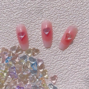 Detail of coffin-shaped nail tips with pink gradient and a 3D translucent heart gem