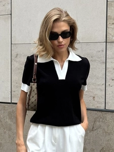 Détail d'un polo en maille noir avec col contrasté blanc dans un style minimaliste