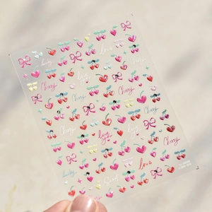 Detail view of 3D nail stickers featuring cherry, pink bows, and crystal rhinestones