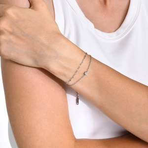 Bracelet double rang en argent avec un zircon rond clair sur un poignet féminin