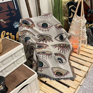 Bohemian woven blanket with colorful eye patterns and fringe on a wooden pallet