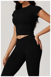 Dettaglio del set yoga nero con vita alta incrociata e crop top sportivo vestibilità slim