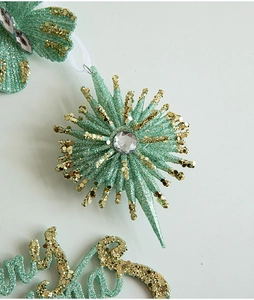Close-up of mint green star ornament with gold glitter and central gemstone detail