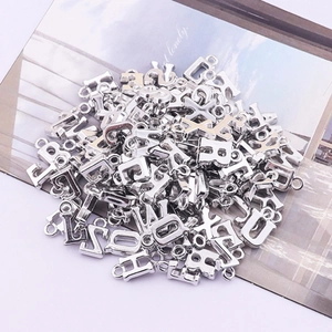 Detail of silver metallic alphabet pendants stacked on a vintage aesthetic background