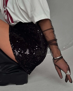 Détail de mode d'une mini-jupe à paillettes noires avec un t-shirt blanc et des bottes
