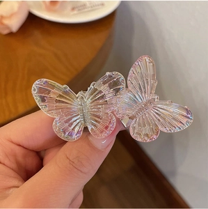 Close-up of glittery butterfly hair clips with iridescent pink and transparent wings