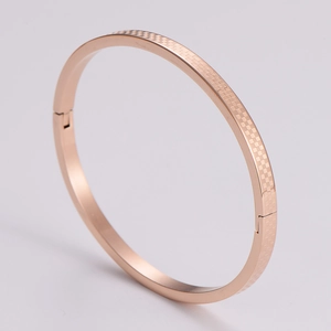 Detail of rose gold bangle with textured checkerboard pattern and side clasp design