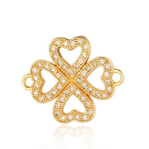 Detailed macro view of a gold four-leaf clover connector with clear cubic zirconia stones