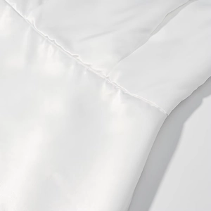 Close-up of white satin fabric texture and premium stitching details on a long dress