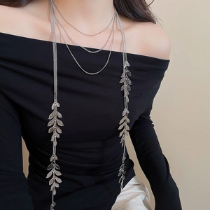 Macro view of multi-layer silver tassel necklace with leaf pendants on a black dress
