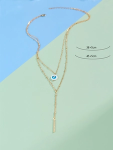 Detailed view of gold double-layer necklace with Evil Eye pendant and Y-shaped tassel
