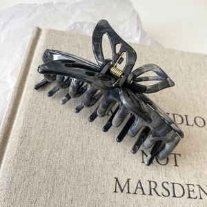 Detail of a butterfly hair claw clip with black marble texture on a linen book
