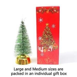 Miniature green flocked Christmas tree with golden base and a red festive gift box